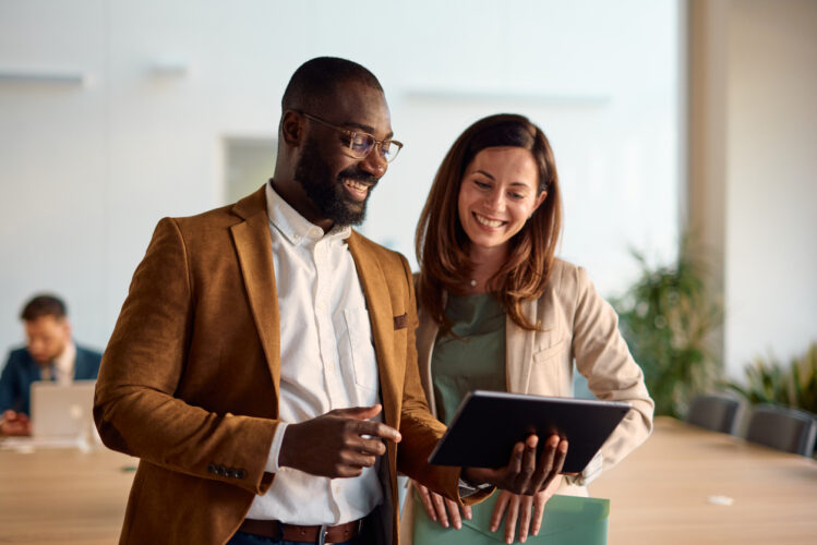 Photographie de deux personnes souriantes regardant une tablette graphique.